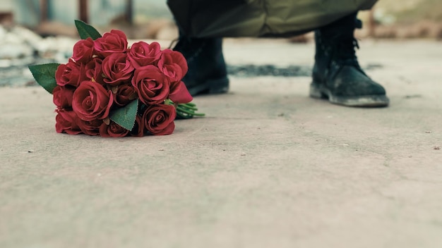 El hombre inclina un ramo de flores rojas en el suelo