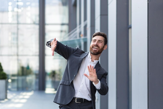 Un hombre independiente exitoso en un traje de negocios baila cerca de la oficina celebra un trato ganador y un buen final para la jornada laboral