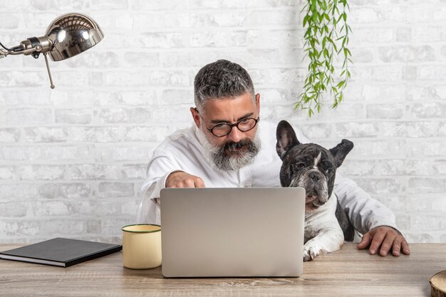 Hombre independiente que trabaja desde casa con su perro sentados juntos en la oficina