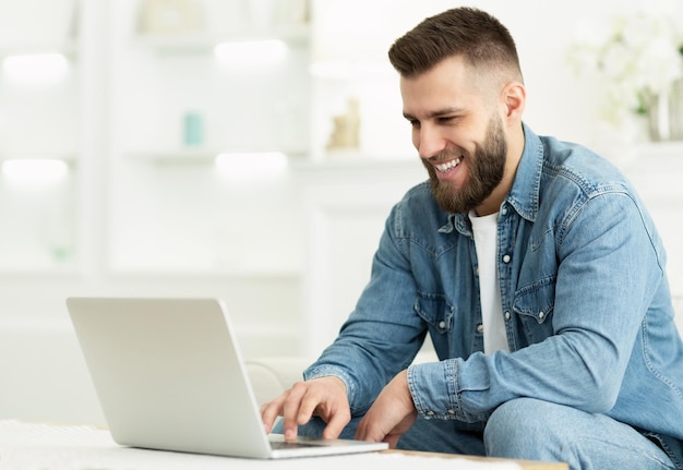 Hombre independiente que trabaja en la computadora portátil en línea en casa