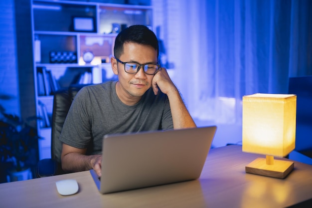 Hombre independiente trabajando en una computadora portátil En casa por la noche Hombre independiente sonriendo y relajándose después de terminar el trabajo en casa por la noche Trabajo independiente y concepto de trabajo desde casa