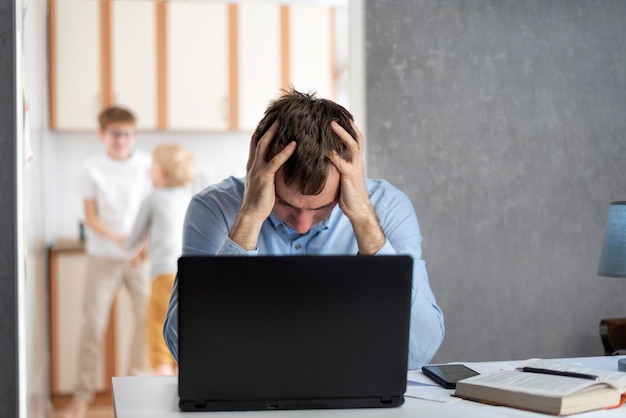 Hombre independiente trata de trabajar en casa con niños. Los hijos interfieren con el trabajo de los padres. Trabajando desde casa, trabajando de forma remota.