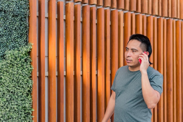 Hombre indígena caminando por la calle mientras habla por teléfono celular