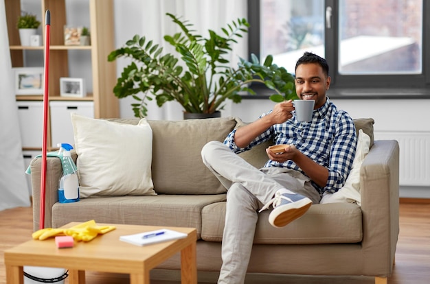 Foto hombre indio bebiendo café después de limpiar la casa