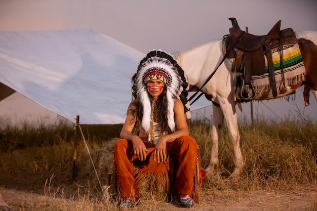 Foto hombre indio estadounidense con tocado y maquillaje con su caballo