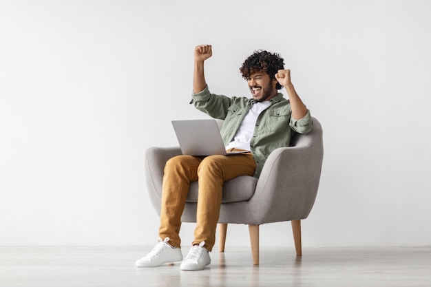 Hombre indio feliz charlando en línea usando una computadora portátil