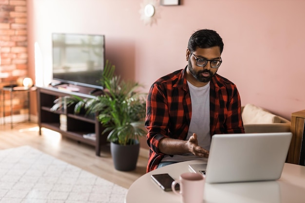 Hombre indio feliz independiente o empresario tiene videoconferencia hablando trabajando de forma remota en línea en la oficina en casa videollamada y concepto de diversidad