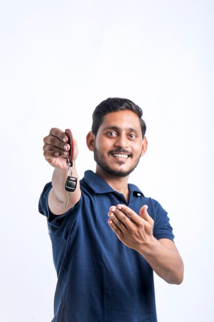 Hombre indio joven que sostiene la llave en la mano sobre el fondo blanco.