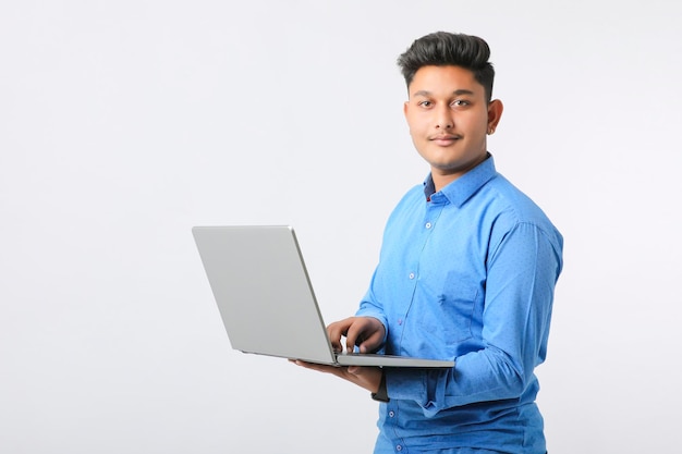 Hombre indio joven que usa la computadora portátil sobre el fondo blanco.