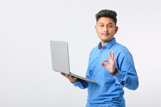 Hombre indio joven que usa la computadora portátil sobre el fondo blanco.