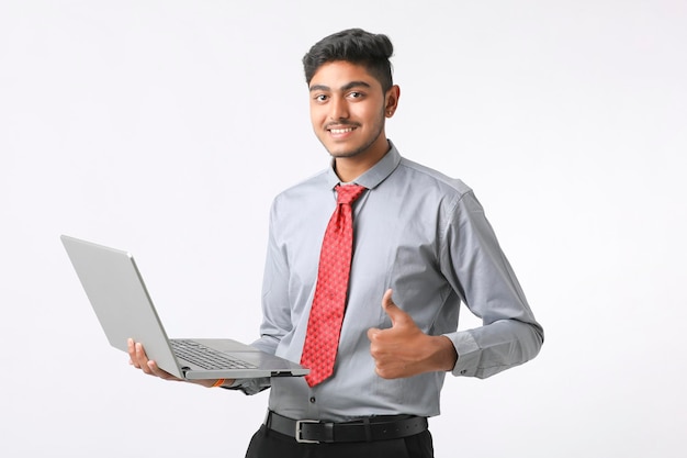 Hombre indio joven que usa la computadora portátil sobre el fondo blanco.