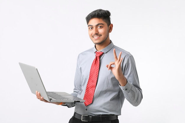 Hombre indio joven que usa la computadora portátil sobre el fondo blanco.