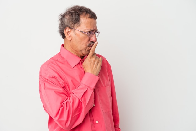 Hombre indio de mediana edad aislado sobre fondo blanco manteniendo un secreto o pidiendo silencio.