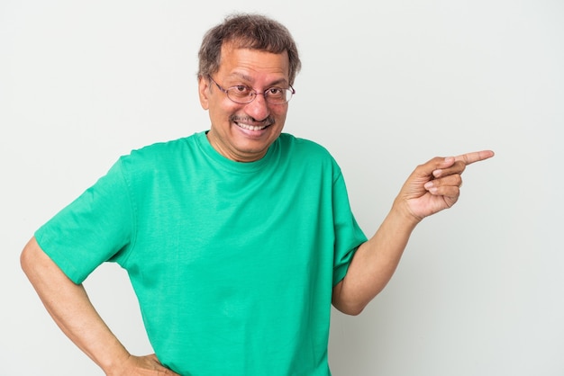 Hombre indio de mediana edad aislado sobre fondo blanco sonriendo alegremente apuntando con el dedo índice.