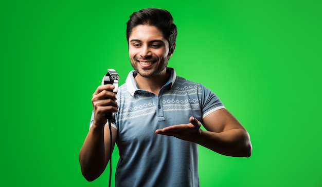 Hombre indio o asiático que se afeita la barba con una podadora eléctrica o una podadora de pie aislado