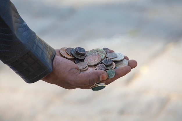 Hombre indio sosteniendo monedas antiguas en sus manos cerca de la India