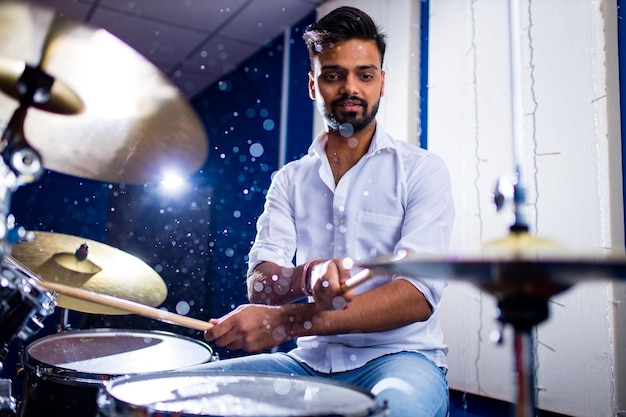 Hombre indio tocando los palos de batería de cerca en el estudio de grabación