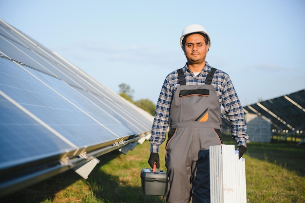 Hombre indio en uniforme en una granja solar Ingeniero energético competente que controla el trabajo de las células fotovoltaicas