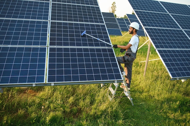 Hombre indio en uniforme trabajando cerca del panel solar