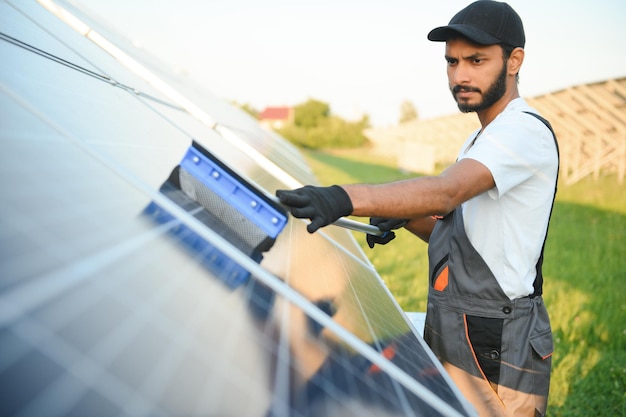 Hombre indio en uniforme trabajando cerca del panel solar