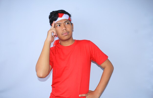 Hombre indonesio pensando y haciendo una lluvia de ideas para una idea creativa con las manos en la cabeza usando una camiseta roja