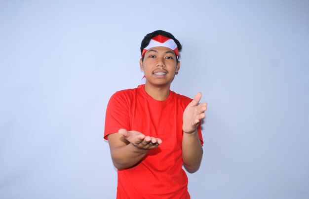 El hombre indonesio presenta un gesto con una cara pacífica y feliz con una camiseta roja y una diadema