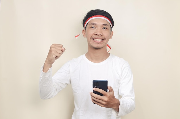 Hombre indonesio sonriendo mientras sostiene un teléfono móvil durante la celebración del día de la independencia