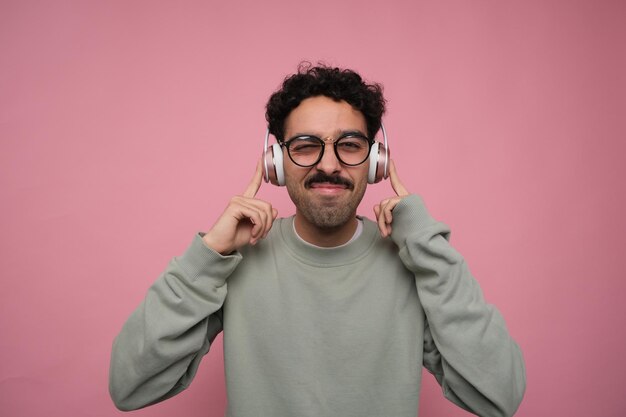 Un hombre infeliz escuchando música con auriculares sin disfrutarla apuntándose los oídos con el dedo