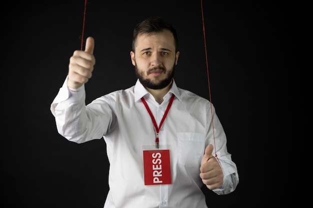 Hombre infeliz con insignia de prensa mostrando como signo como marioneta