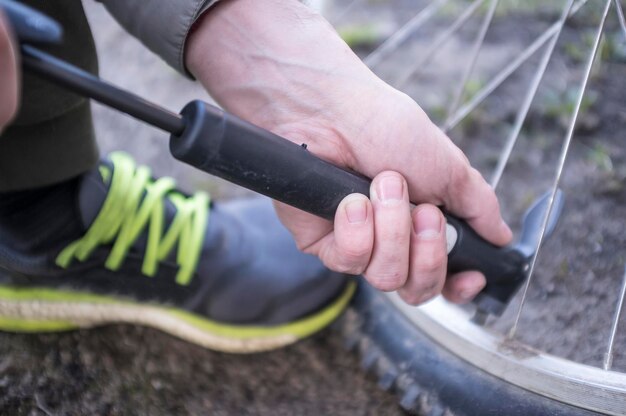 Hombre infla rueda de bicicleta con una bomba. De cerca