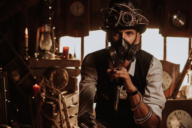 Hombre de ingenieros en un traje steampunk con un sombrero de copa con gafas y una máscara de gas