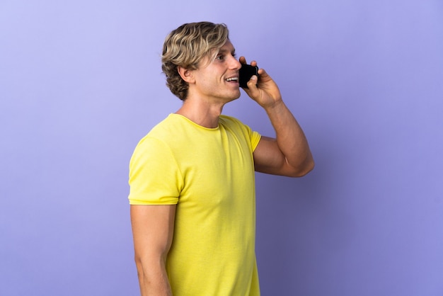 Hombre inglés sobre fondo púrpura aislado manteniendo una conversación con el teléfono móvil