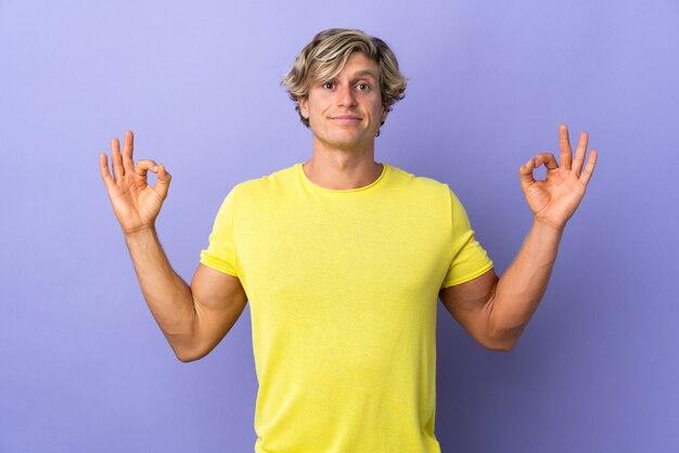 Hombre inglés sobre pared púrpura aislada en pose zen