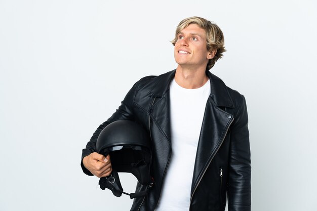 Hombre inglés sosteniendo un casco de motocicleta pensando en una idea mientras mira hacia arriba