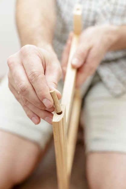 El hombre inserta una clavija de madera en un trozo de madera, primer plano