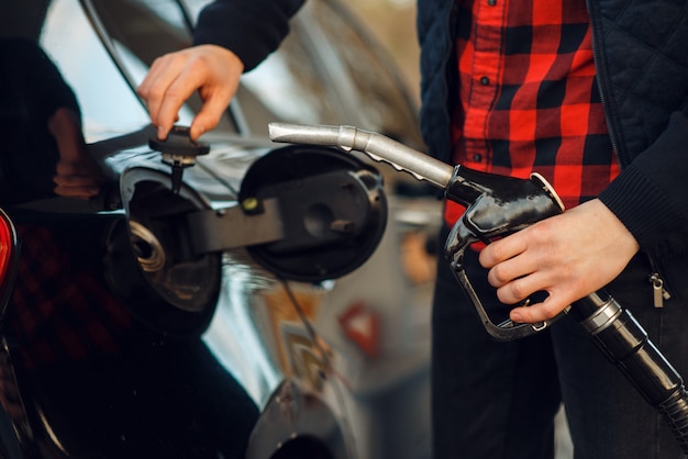 El hombre inserta la pistola en el tanque del coche en la gasolinera