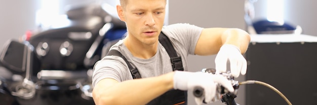 El hombre inspecciona la motocicleta en el primer plano del taller de reparación