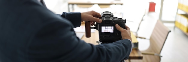 El hombre instala una cámara profesional en un trípode para tomar una foto de una mesa vacía en una oficina moderna