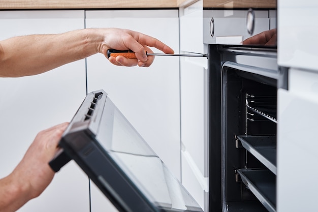 Hombre instalando horno eléctrico en la cocina