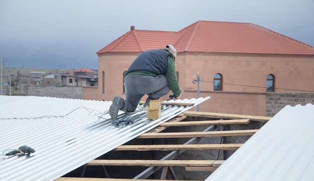 Hombre instalando láminas de tejas metálicas de techo