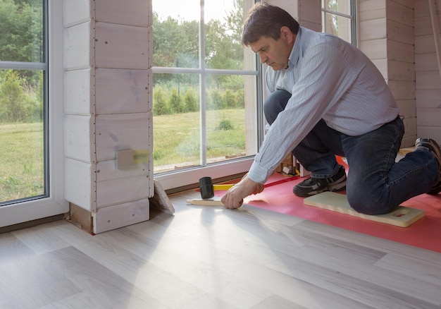 Hombre instalando nuevo piso de madera laminada