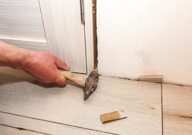 Hombre instalando las puertas con un martillo. Agujeros en la pared. Trabajos de reparación. Mantenimiento en el departamento.