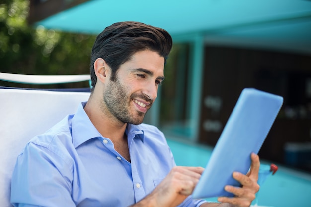 Hombre inteligente con tableta digital junto a la piscina