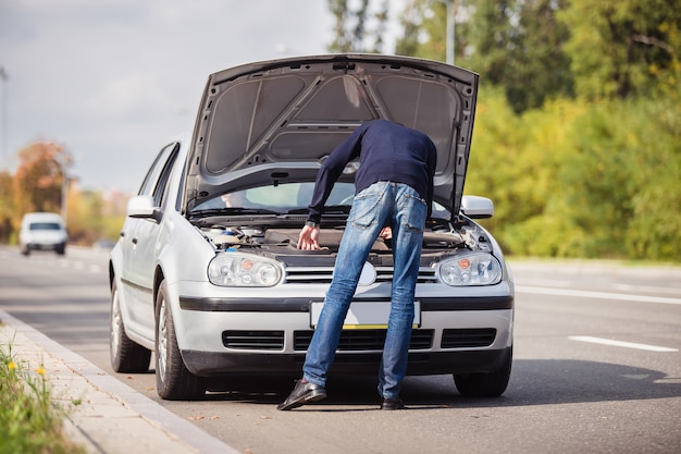 Foto un hombre intenta reparar el auto en la carretera
