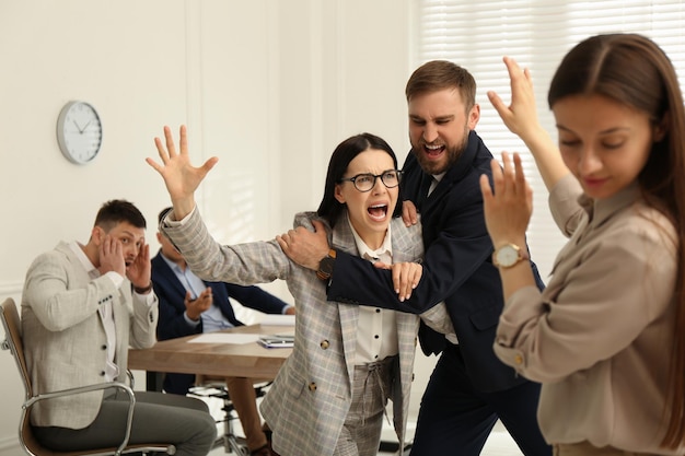 Hombre interrumpiendo pelea de colegas en el trabajo en la oficina