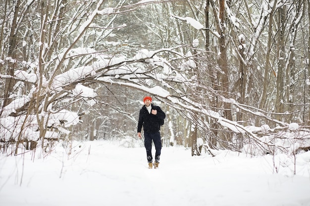 Un hombre en el invierno en el bosque un turista con una mochila pasa por el bosque en invierno invierno