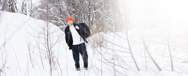 Un hombre en el invierno en el bosque. Un turista con mochila recorre el bosque en invierno. Ascenso invernal.