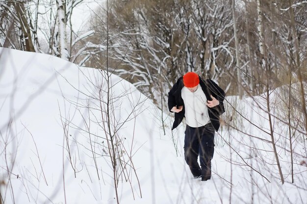 Un hombre en el invierno en el bosque. Un turista con mochila recorre el bosque en invierno. Ascenso invernal.