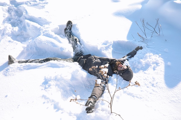 Un hombre en invierno en la calle. el chico camina por la carretera de  invierno. un hombre joven con una chaqueta de plumas está saltando en la  nieve.