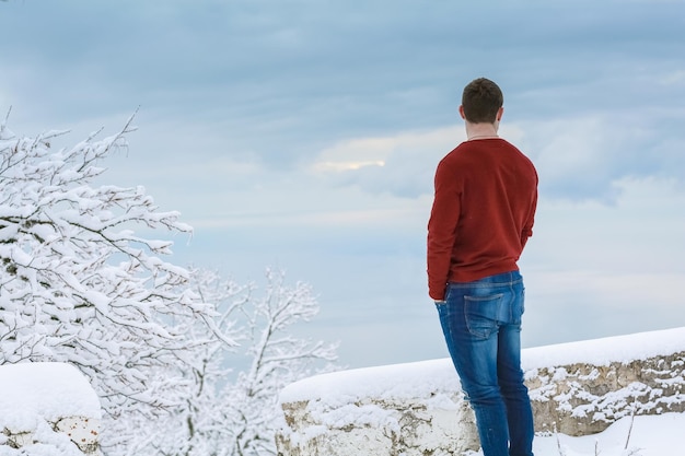 Un hombre en invierno está de espaldas a la cámara y mira el horizonte.